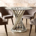 Clear glass round dining table with brushed silver hourglass base in a dining room setting