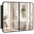 Black-framed double door bathroom mirror cabinet reflecting a bathtub and window