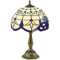 Stained glass table lamp with a baroque scroll pattern shade on an ornate base, studio shot