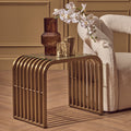 Matte gold slatted end table with clear glass top styled beside a sofa in a living room