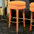 Orange velvet round bar stools at a kitchen island