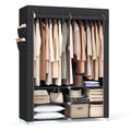 Black portable wardrobe filled with clothes, bags and folded linen on a white background