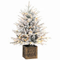 Snow-flocked pre-lit table Christmas tree in a wood-effect base on white