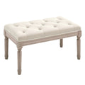 Cream white button-tufted bench with distressed wooden legs on a white background