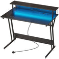 Black two tier gaming desk with blue LED lighting and a UK plug on a white background