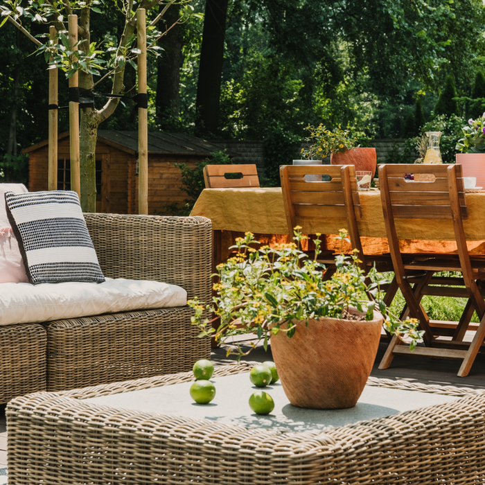A stylish and functional garden with a comfy wicker sofa seating area and a wooden dining table and chairs