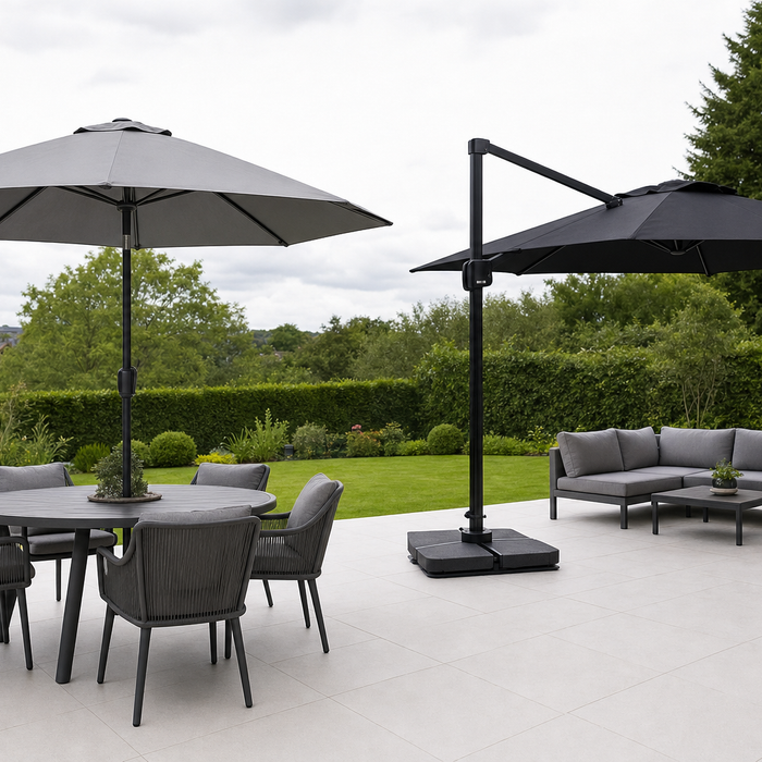 Grey centre pole parasol over a dining table and black cantilever parasol over a garden sofa side by side on a patio