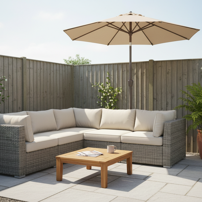 L-shaped modular rattan garden sofa with neutral cushions, low coffee table and compact parasol on a small bright UK patio with potted plants and grey paving