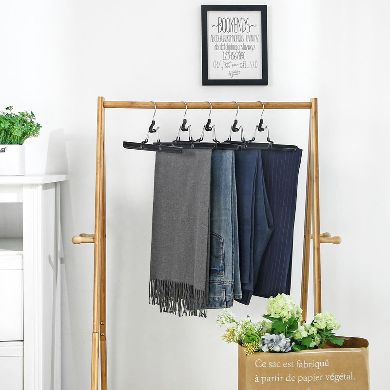 Black skirt hangers holding trousers and a scarf on a wooden clothes rail