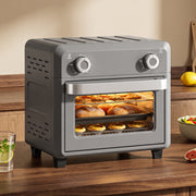 Grey air fryer oven on a wooden worktop baking pastries