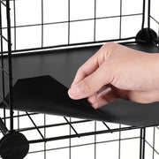 Close-up of a hand lifting a black plastic base panel out of the wire mesh frame