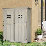 Grey wooden garden shed against a rendered wall beside a wall lantern