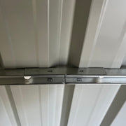 Close-up inside the shed of the pale roof lining and the bolted galvanised steel roof beam