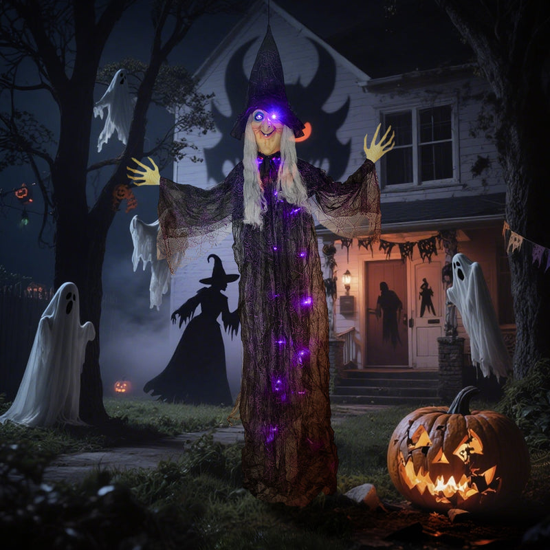 Hanging witch decoration displayed outside a house at night with ghost decorations and pumpkins