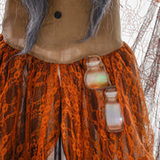 Close-up of the witch's glowing potion bottles hanging at her waist