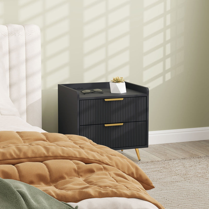 Bedside table beside a bed with a quilted throw and reading glasses on top
