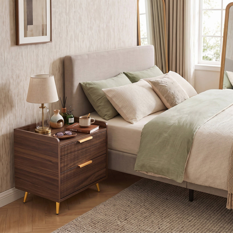Bedside table beside a bed with soft bedding and a lamp in a bright bedroom