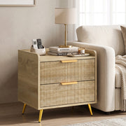 Bedside table beside a sofa arm holding a lamp, books and remote control