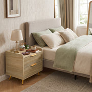 Angled view of the bedside table in a bedroom beside an upholstered headboard