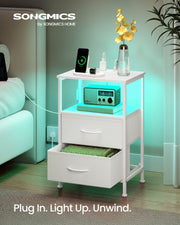 Cloud white bedside table beside a sofa with green LED lighting, a radio on the shelf and an open drawer