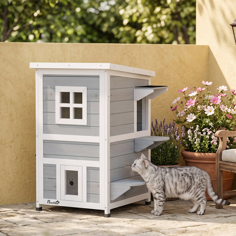 Cat approaching the grey 2-floor PawHut cat house beside potted flowers on a patio