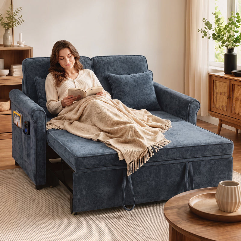 Woman reading under a blanket on the dark blue sofa bed set to lounger mode