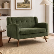 Dark green loveseat sofa styled in a living room with bookshelves
