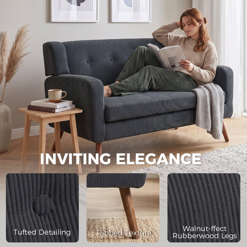 Woman reading on the dark grey loveseat with tufted detailing and walnut-effect leg insets