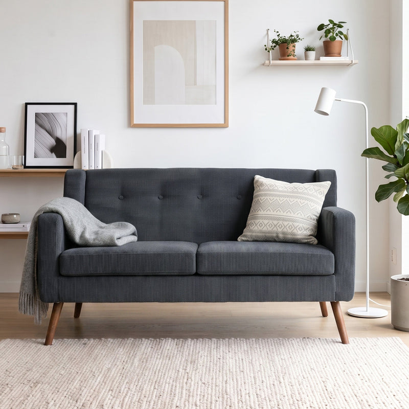 Dark grey corduroy sofa with wooden legs styled in a bright living room