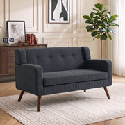 Dark grey corduroy loveseat beside a wooden sideboard in a panelled living room