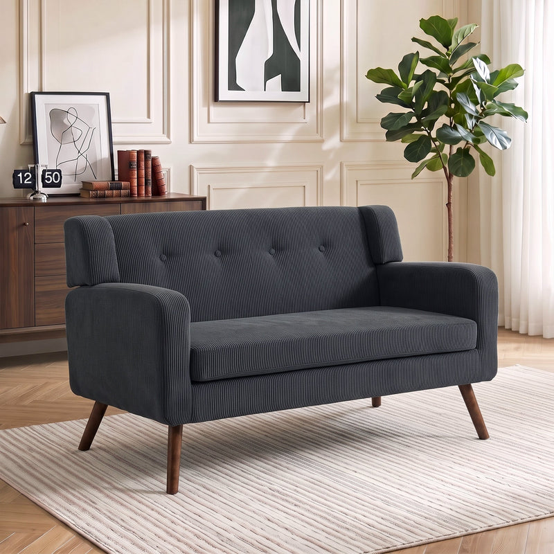 Dark grey corduroy loveseat beside a wooden sideboard in a panelled living room