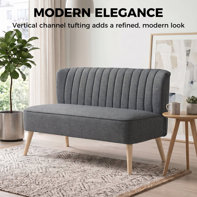Channel-tufted high back of the dark grey sofa in a styled living room
