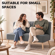 Couple chatting over coffee on the 2 seater sofa in a small living space