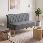 Grey 2 seater sofa in a living room beside a floor lamp, plant and wicker basket