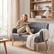 Woman reading a book on the grey sofa with a cream throw blanket