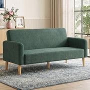 Dark green velvet sofa styled in a living room with a rug, curtains and fresh flowers