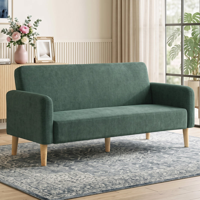 Dark green velvet sofa styled in a living room with a rug, curtains and fresh flowers