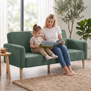 Mother and daughter reading together on the dark green sofa in a living room