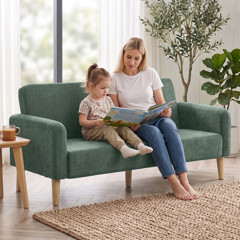 Mother and daughter reading together on the dark green sofa in a living room