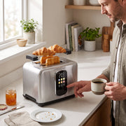 Man in a bright kitchen touching the toaster controls with croissants on the rack