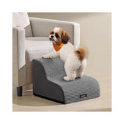 Small dog climbing the Feandrea 2-step dog stairs beside an armchair