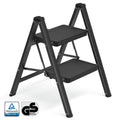 Black 2-step folding ladder standing open, with TUV Rheinland and GS safety marks