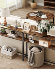 Console table behind a sofa in a living room holding a lamp, photo frames and flowers