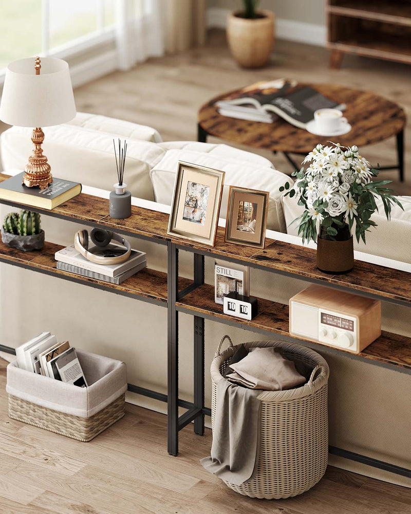 Console table behind a sofa in a living room holding a lamp, photo frames and flowers