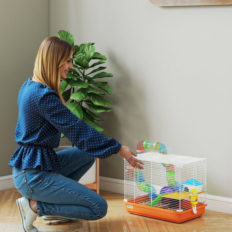 Woman placing the orange and white hamster cage on the floor in a living room