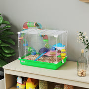 Green PawHut hamster cage with bedding, set on a wooden shelf beside a plant
