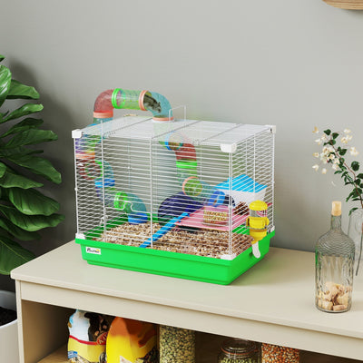 Green PawHut hamster cage with bedding, set on a wooden shelf beside a plant