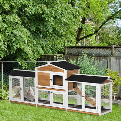 White 2-tier rabbit hutch with black asphalt roof and rabbits inside, set up in a garden
