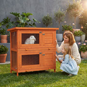 Lifestyle photo of a family with a rabbit inside the hutch outdoors on grass