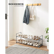 Grey shoe rack in a hallway holding shoes below a wall-mounted coat rail